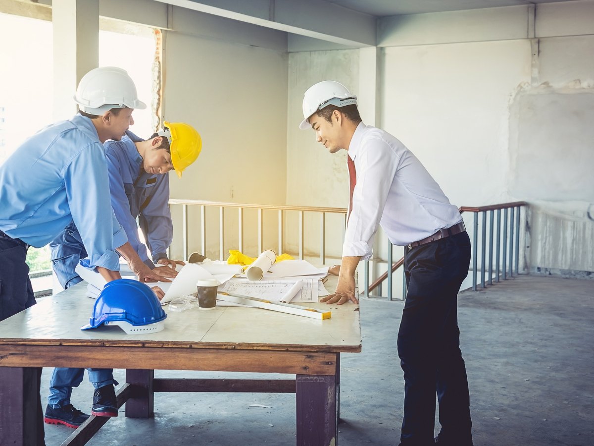 Team of engineers and construction workers discussing the structural plans on a table at building site.